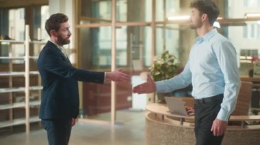 Ofiste tokalaşan iki beyaz erkek iş ortakları selamlaşıyorlar. Merhaba el sıkışma, gülümseyen el sıkışma, gülümseyen iş adamları. Erkek iş ortaklığı.