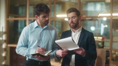 Profesyonel iş adamları yetişkin Kafkas erkek iş arkadaşları şirket belgelerini tartışıyor evrak anlaşmasını analiz ediyor ofiste iki erkek lider personel iş planı danışmanlığı notları yazıyor