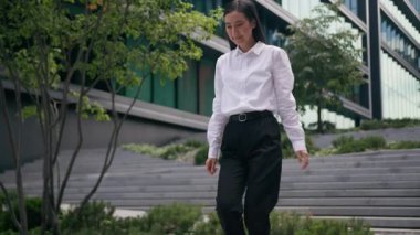 Merdivenlerden inen mutlu Asyalı kadın merdivenlerden aşağı iniyor. İş kadını bayan çalışanın başarısını kutluyor. Kariyer zaferini dışarıda kutluyor.