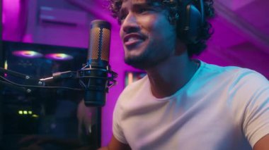 Hintli Arap Latin adam mikrofon etkileyicisi bağırarak konuşan heyecanlı adam oyuncu flamalı radyo sunucusu duygusal blogger vlogger çevrimiçi video oyunu bağımlısı stüdyoda oyun bağımlısı