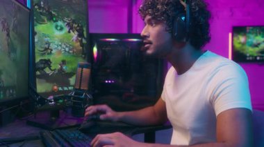 Odaklanmış Arap Hindistanlı Latin adam konuşuyor video oyunu oynayan bilgisayar teknisyeni mutlu erkek sunucu kulaklık takıyor Neon blog blogu internet sunucusu hobisi