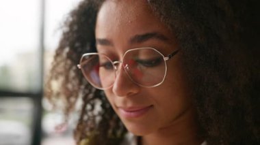 Üniversitede Afro-Amerikalı bir kız öğrencinin portresi. Güzel, zeki, etnik bir kadın. Sınav hazırlıklarında kameraya bakıp gülümsüyor.