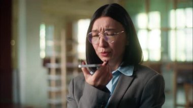 Hüzünlü Asyalı iş kadını ofis müdürü Koreli Çinli kız ses mesajı gönderdi. Akıllı telefon konuşmaları, fabrika endüstrisinde hoparlör konuşmaları.