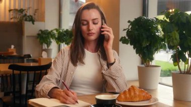 İş kadını, kafe masasında telefon görüşmesi şirket iş görüşmeleri danışman bayan iş kadını, akıllı telefon yazma notları ile müşteriyle konuş ağ yazma, bilgi yazma görevi planlama.