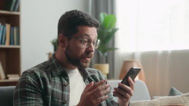 Beyaz, yetişkin bir erkek, evde oturmuş cep telefonuna bakıyor ve futbol maçı seyrediyor. Kumarhane bozuk sonuç için bekliyor. Akıllı telefon uygulaması.