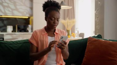 Kafası karışık, mutsuz, üzgün, Afrikalı, Amerikalı iş kadını, kadın, iş kadını, depresyonda, müşteri ev sahibi, cep telefonu kullanıcısı, uygulamayla kumar oynuyor, evde kayıp para dolandırıcılığı yapıyor.