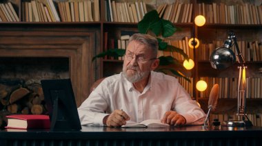Kafkasyalı yaşlı adam not defteri yazıyor. Emeklilere, olgun erkek ofis işadamlarına evrak işleri planlıyorlar. Belge masasında çalışıyorlar.