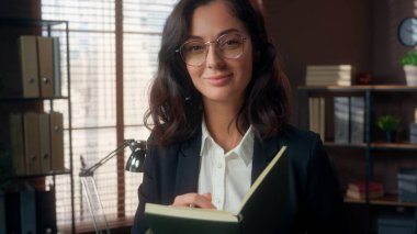 Kafkas iş kadını elinde kalem kalem tutan gözlük takıyor. Not defteri yazıyor. Ofiste çalışan kadın finans müdürü.