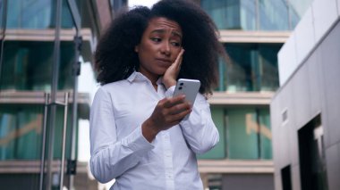 Şok olmuş, afro-amerikalı kadın, iş kadını, dışarıda cep telefonu, akıllı telefon, kötü haber, hata, işçi, şehir merkezindeki girişimci.