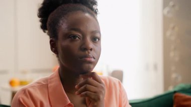 Düşünceli, etnik Afrikalı, Amerikalı iş kadını düşünceli, kadın, kadın, iş kadını, ev sahibi. Düşünen ev sahibi, kararının belirsiz olduğunu düşünüyor. Ev kanepede derin düşüncelere dalmış çene hareketi yapıyor.