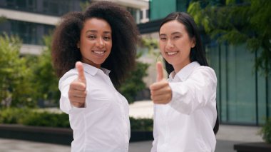 İki Afro-Amerikalı Asyalı Çinli Japon kadın iş kadını gibi başparmak gösteriyorlar. İş kadınları danışmanlık tavsiyesi. Çok ırklı meslektaşlar.