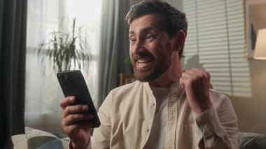 Kafkas mutlu kazananı heyecanlı iş adamı duygusal ev sahibi erkek şampiyon online kumar cep telefonu mesajı iyi şans akıllı telefon zaferi çığlığı evde kutlayın
