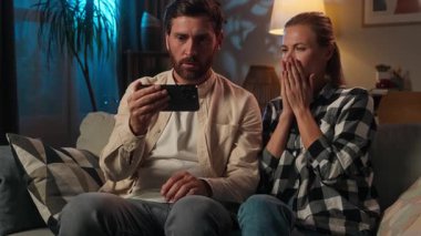 Korkak çift, beyaz kadın, koca karı koca, akıllı telefondan video izliyorlar. Gece uykusuzluğu, korku filmi, cep telefonu, stres, hayal kırıklığı, kötü haber.