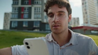 Neşeli Kafkasyalı genç adam elinde akıllı telefonuyla sosyal medya online sohbet uygulaması aletleri gülümseyen öğrenci işadamı iş dünyası teknolojisi bağlantı şehirleri açık hava eğlence mesajları