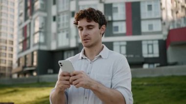 Kafkasyalı genç adam cep telefonu kullanıyor. Akıllı telefon erkek. Şehir dışında düşünceli iş adamı. Elinde cep telefonu tutan düşünceli adam.