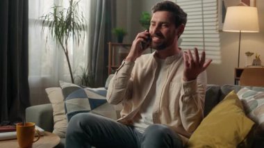 Beyaz erkek ev sahibi, rahat rahat koltukta rahatla gülümse, erkek mutlu ol, cep telefonu ara, sohbet et, sohbet et, cep telefonu sipariş et, yemek siparişi ver.