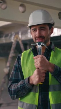 Neşeli, aktif, beyaz bir adam elinde çekiç tutarken mikrofon kullanıp şarkı söylüyor. Müzikten zevk alıyor. Erkek, mimar, müteahhit, inşaat işçisi inşaatında çalışıyor.