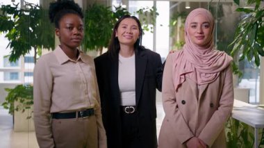 Çok ırklı, neşeli, güler yüzlü iş kadınları üç farklı etnik arkadaş kız öğrenciler Asyalı, Müslüman iş kadınları ofis bayan iş arkadaşları, kadın iş arkadaşları, kadın ortaklık pozu veriyorlar.