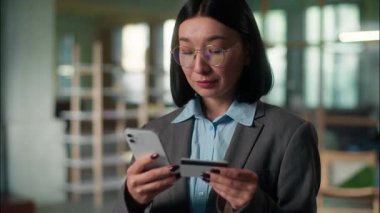 Asyalı Koreli Koreli Japon kadın iş kadını girişimci mühendis ofisteki internet alışverişinde internet bankası uygulaması satın alıyor kredi kartı ödemesi cep telefonu