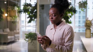Öfkeli etnik iş kadını Afrikalı Amerikalı iş kadını ofiste cep telefonu daktilo eden bayanı sinirlendirdi kötü haber mesajlaşması, sohbet mesajı olumsuz cep telefonu mesajı