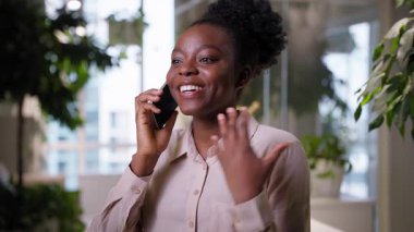 Duygusal olarak mutlu gülümseyen Afrikalı Amerikalı etnik iş kadını ofis şirketinde konuşan heyecanlı cep telefonu kızı evet, neşeli iş kadını.