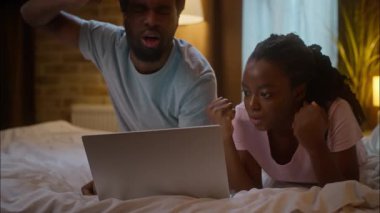 Üzgün, sinirli, Afrikalı, Amerikalı, etnik çift, aile sevgilisi, dizüstü bilgisayarda uzanmış spor maçı seyrediyor.