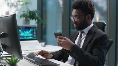 Mutlu Afro-Amerikan adam elinde bankacılık kredi kartı tutuyor tüketici ödemesi alıyor bilgisayar alıcısı iş adamı alışveriş yapıyor işletme müdürü ofis müşterisi satın alıyor