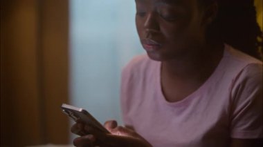 Mutsuz, ciddi, etnik, Afrikalı, Amerikalı kadın, serbest kadın müşteri cep telefonu kullanıyor. Mesaj yazıyor, olumsuz sohbet yazıyor.