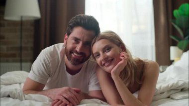 Gülümseyen beyaz çift, sabah birlikte yatıyorlar. Kaygısız eş, kadın, kız arkadaş. Yatak odasında kameraya bakıyor.