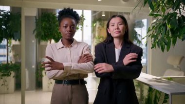 Kendine güvenen iş kadınları iş ortakları çok ırklı Afrikalı kadın iş arkadaşları Amerikalı kız Çinli iş arkadaşları iş arkadaşlarının elleri çapraz pozlarda gülümsüyor gibi görünüyor.