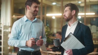 Erkek arkadaşlar iş arkadaşları Kafkasyalı iş adamları birlikte kahve içerler ofiste gülümseyen iş adamları ortaklar şirket sohbetlerinde haberleri tartışırlar.
