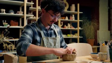 Profesyonel heykeltıraş çömlekçi Kafkas erkek öğretmen ressam ustası çömlek atölyesinde kil çevrimiçi ana sınıfı modelliyor dizüstü bilgisayarlı sanat rehberliği videosuyla el işi eğitimi hazırlıyor.