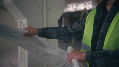 Profesyonel Kafkasyalı müfettiş müteahhit adam teknisyen mühendis erkek taslak planlama tasarımcısı işçi tasarımcısı inşaat manufactory 'daki şema teftiş binasını analiz ediyor