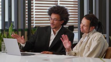 İki çok ırklı Afrikalı Amerikalı erkek iş ortağı erkek iş ortağı erkek iş adamı şirket video konferansı hakkında konuşuyor ofiste web kameralı bilgisayara çevrimiçi görüşme kağıtları gösteriliyor