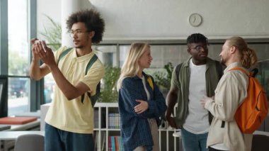 Üniversite koridorunda konuşan çok ırklı öğrenci arkadaşları Afrikalı Amerikalı adam sosyal medya vlog 'u için fotoğraf selfie cep telefonu pozu veriyor.