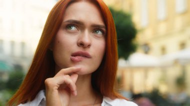 Beyaz, çekici bir kadın, düşünceli, kadın, iş kadını, turist, açık hava portresi. Planlama fikri, soru. Çene üstüne el ele tutuşun.