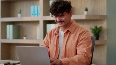 Ofiste bilgisayar işi yapan Kafkasyalı erkek, iş adamı, iş adamı, dizüstü bilgisayar yazan dizüstü bilgisayar tasarımcısı, masa başında çalışan mutlu işveren, PC arama verisi internet e-ticaretini kullanan, gülümseyen biri.