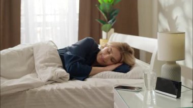 Uykucu Kafkasyalı kadın uyanıyor. Sabah uyanıyor. Uyanmış bir kadın. Zaman ayarlı cep telefonu kontrol ediyor.