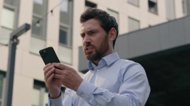 Kızgın, orta yaşlı, olgun iş adamı, şehir merkezinde akıllı telefon kullanmaktan rahatsız olan iş adamı, kızgın işveren, cep telefonu, spam mesajı, dışarıda çalışmaktan rahatsız oluyor.