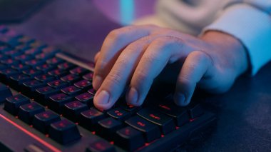 Çevrimiçi çalışan, bilgisayar klavyesini kapatan, İnternet 'te çalışan, e-öğrenen bilgisayar korsanı, tanınmayan erkek oyuncu, video oyunu web kodlaması, modern teknoloji neon ışıkları siber-bilgisayar oyunları oynayan.