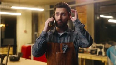 Profesyonel Kafkasyalı sanatçı erkek ahşap ustası mimar konuşan cep telefonu işçisi atölye marangozunun cep telefonu tamircisi ile görüşüyor.
