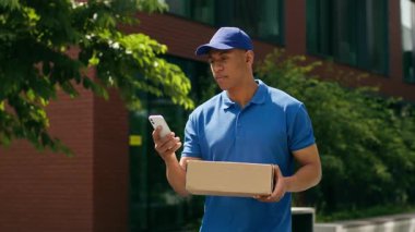 Kafası karışmış Afrika kökenli Amerikalı kurye teslimatçı erkek postacı cep telefonu kontrol adresi internet adresleri akıllı telefon kullanıcısı GPS haritası kullanarak kutu taşıma sorunu kullanıyor.