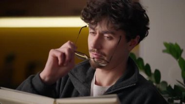 Düşünceli, beyaz adam elinde kitap defteri tutan, ilginç edebiyat romanı okuyan hobi sahibi, boş zamanlarını kitap okuyarak geçiren, gözlük takan, gözlük takan, ev kütüphanesinde düşünen bir adam.