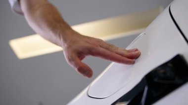 Erkek elini kapat. Tanınmayan adam yakıt deposu kapağına basıyor. Hortum elektrikçisinin şarj ettiği elektrik prizi açık.