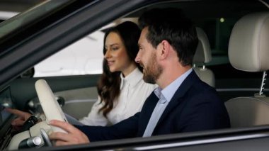 Kafkas erkek alıcı müşterisi, kadın tüccarla konuşuyor. Otomobil kuaföründe yeni bir arabanın içinde oturmuş test sürüşü satın alan otomobil erkeği seçmeyi tartışıyorlar. Kira hizmeti danışmanı kadın danışmanı.