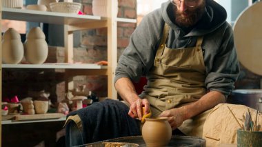 Erkek zanaatkar, sarı süngeri ıslatırken kilden vazo, pürüzsüz kenarlar, çömlek çarkı atölyesi, çömlek seramik atölyesi, nemli kupa, ıslak yaratıcı hobi.