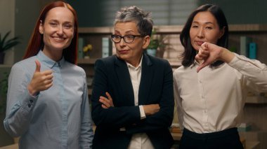 Başparmak işareti gösteren üç kadın. Bilinmeyen, kesin olmayan bir hareket. Çalışanların ofisi, evet ya da hayır.