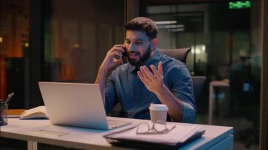 İşadamı Hintli adam gece yarısı çoklu iş adamı ofiste fazla mesai yapıyor cep telefonuyla konuşuyor bilgisayar ticareti, akıllı telefon görüşmeleri, gülümseyen müdür danışmanlık yapıyor.