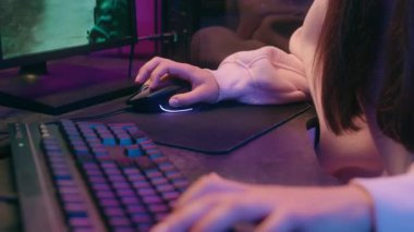 Konsantre kadın oyuncu kız kulaklıkla mikrofon ile konuşan mikrofon yayını bilgisayar çevrimiçi oyununda gece bağımlılığı oyun akışı savaşında neon odasında oynayan kadın oyuncu.