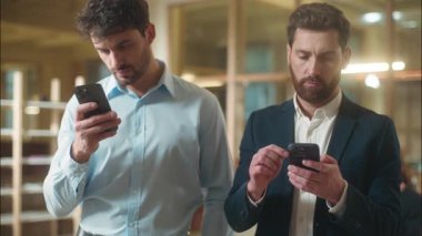 İş adamları Kafkasyalı iş adamları ofis bağımlılığı aletlerinde cep telefonu kullanıyorlar. İki erkek çalışan, akıllı telefon bağımlısı. İnternette iş arkadaşlarını görmezden gelerek sanal mesajlaşmalar yapıyorlar.